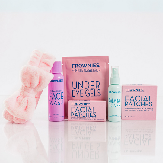 various Frownies skincare products including pink skincare headband with bow, face wash, under eye gels, facial patches, and calming toner spray