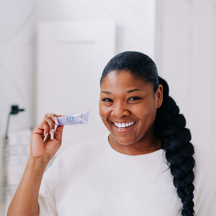 Frownies eye cream being held by a black woman 