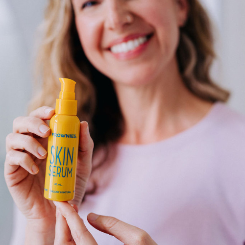 Frownies skin serum being held by a woman who is smiling 