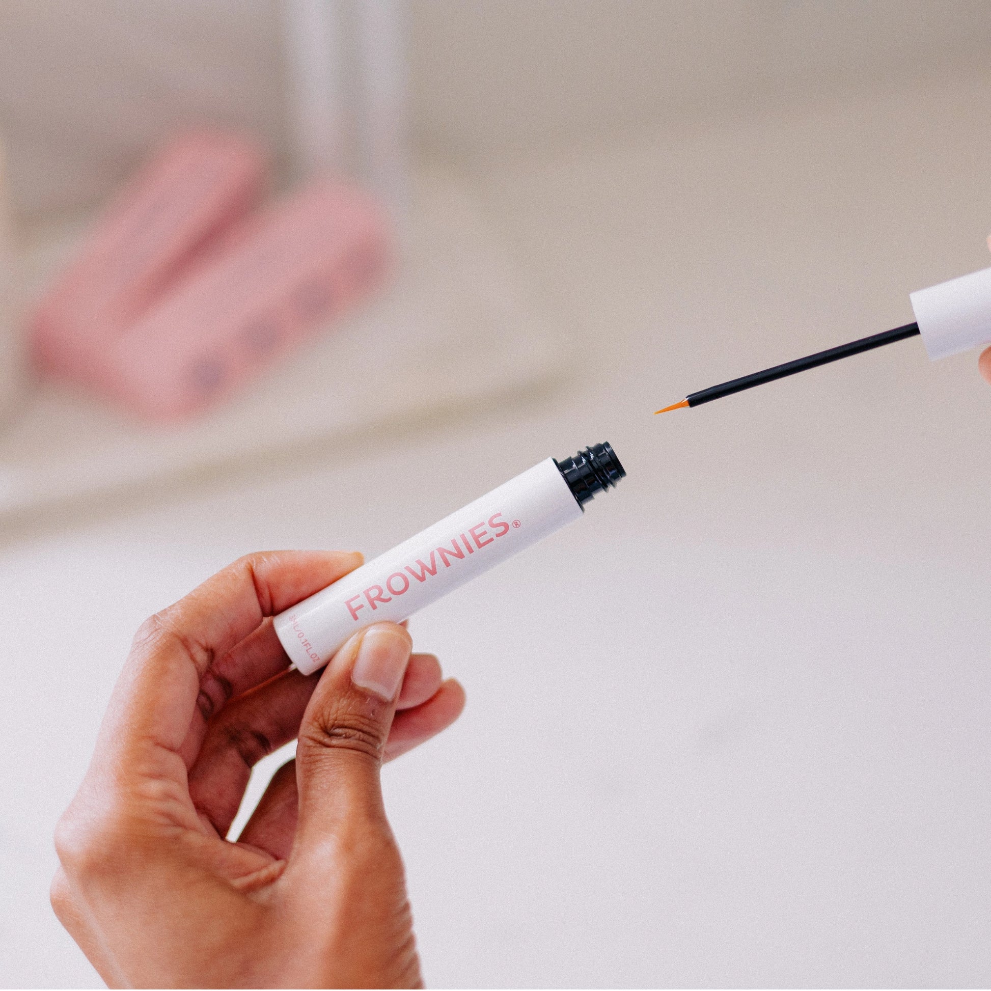 Frownies Eyelash Growth Serum shown being opened and prepared for use.