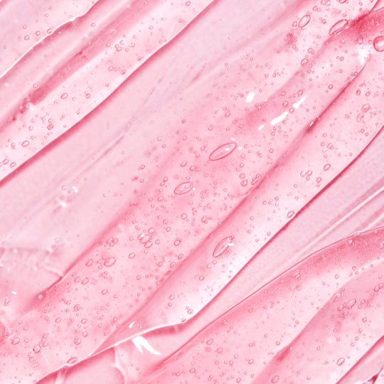 Close-up of a pink surface with intricate water droplets scattered across it, highlighting the texture and sheen of the drops.