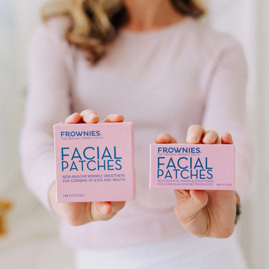 Close-up of a woman holding CEM (Corners of Eyes and Mouth) and FBE (Forehead Between Eyes) facial patches, showcasing the product packaging.