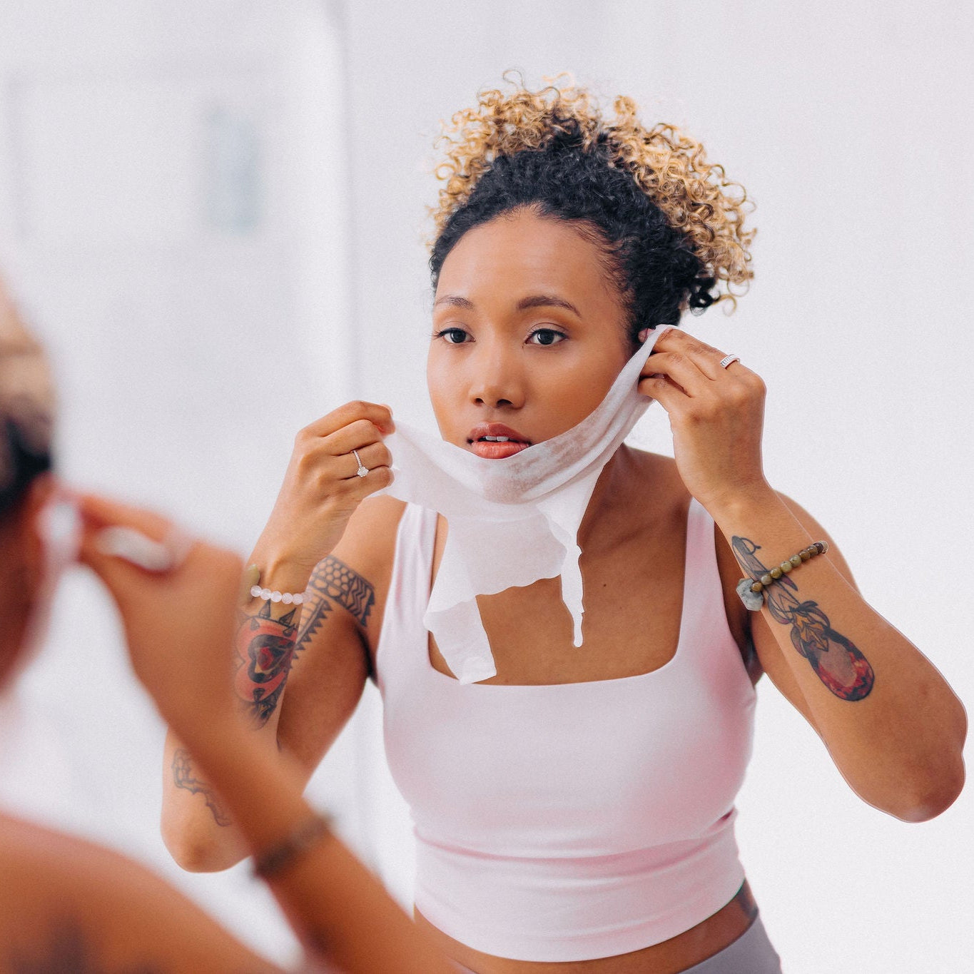 A balck woman shown putting on Frownies chin-up polypeptide mask in the mirror