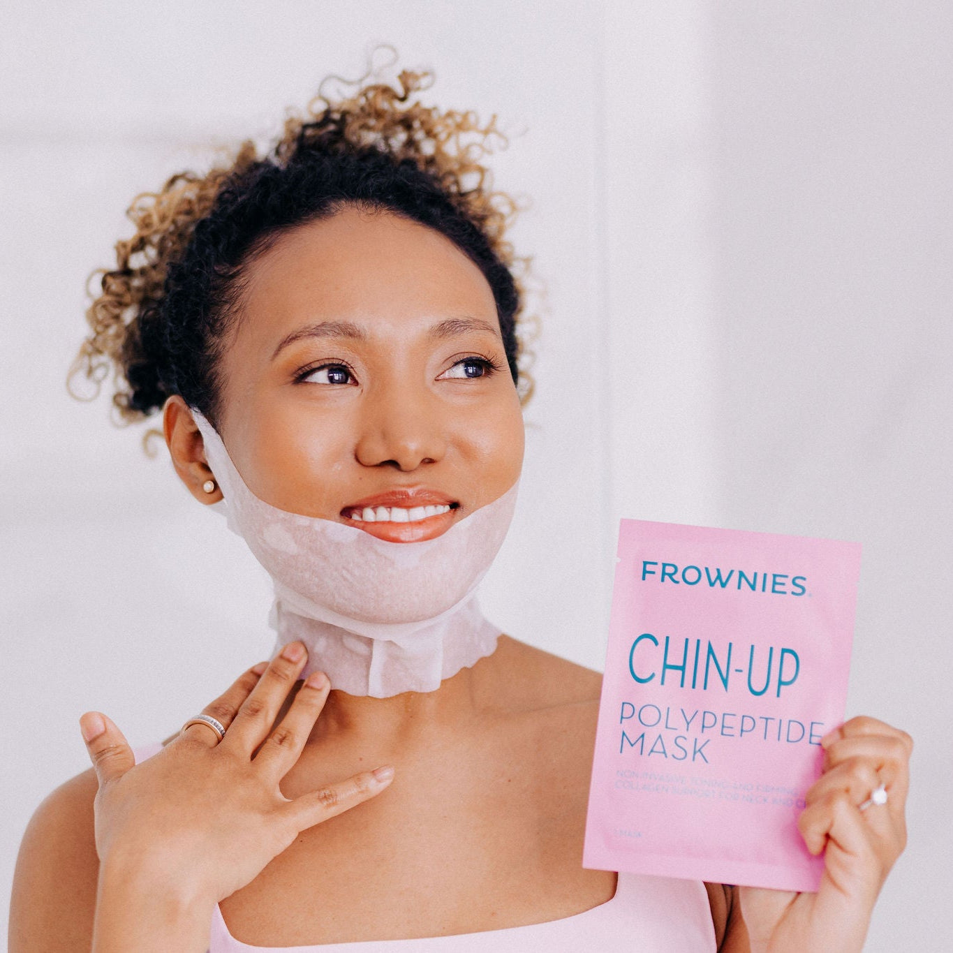 A black woman with curly hair shown wearing Frownies chin-up polypeptide mask