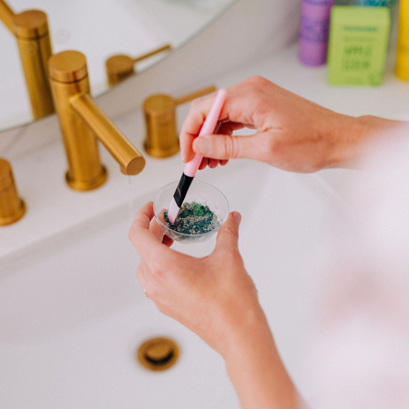 Frownies blue green algae clay mask shown being stirred in the cup to create the final form of the mask before it is applied to the skin 