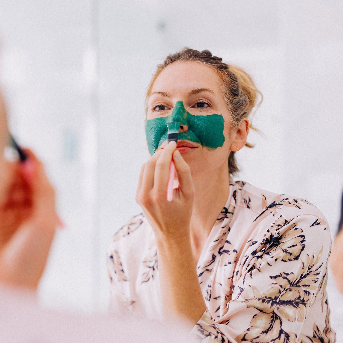 Frownies blue green algae clay mask being applied to a womans face with the brush 