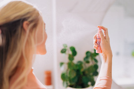 A woman with blonde hair shown spraying Frownies rose water hydrator spray onto her face