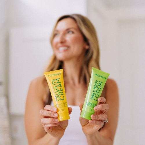 Frownies cellulite cream and daily body lotion being held by a smiling woman 