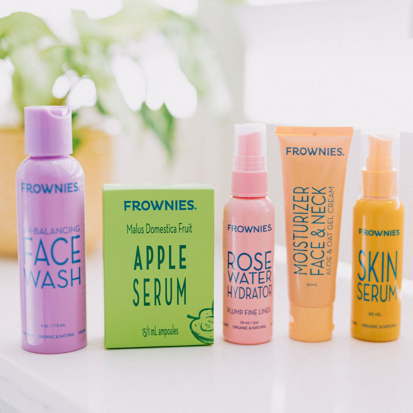 Group of Frownies products - face wash, apple serum, rose water hydrator spray, moisturizer for face and neck, and skin serum 