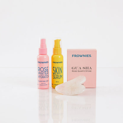 Frownies gua sha rose quartz stone next to Frownies Rose water hydrator spray and skin serum