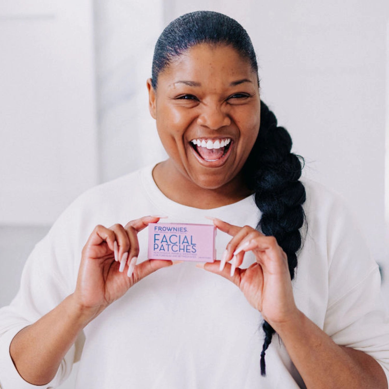 Smiling woman holding Frownies facial patches.