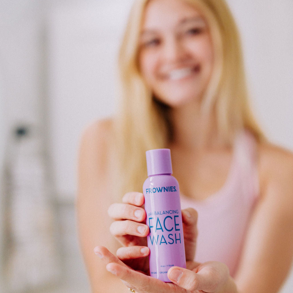 a white woman with blonde hair shown holding Frownies PH balancing face wash 