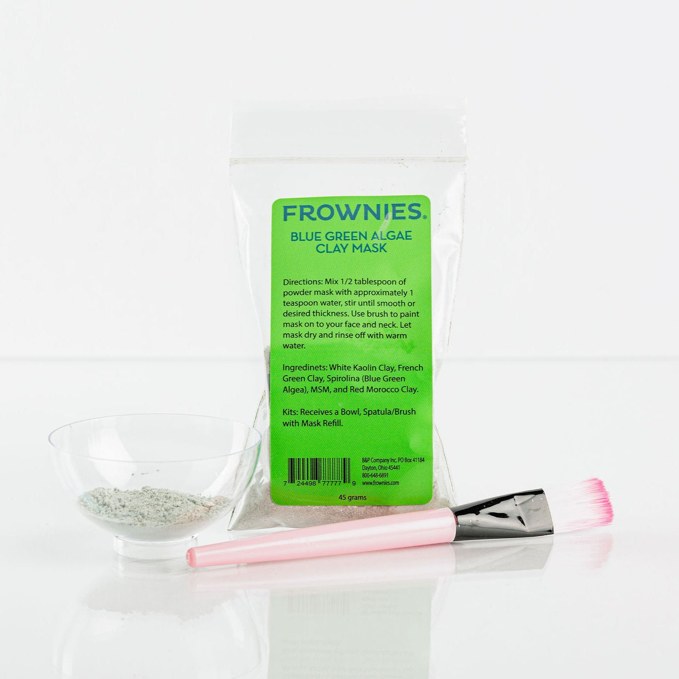 Frownies blue green algae clay mask shown pictured on a clean white background. The cup and brush used for this product are also shown pictured 