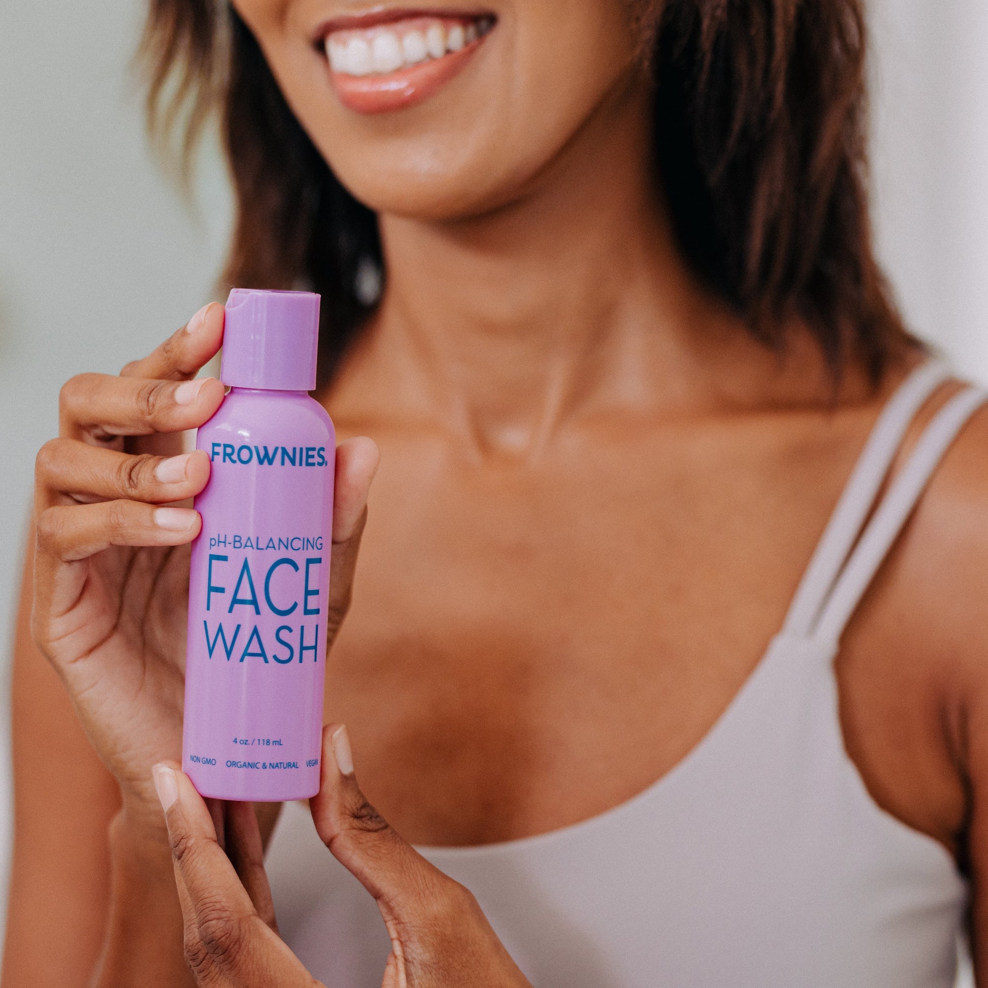 A woman with black hair shown holding Frownies balancing face wash 