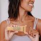 Frownies moisturizer for face and neck with aloe and oat gel cream pictured with a black woman holding the orange container in her hands and smiling 