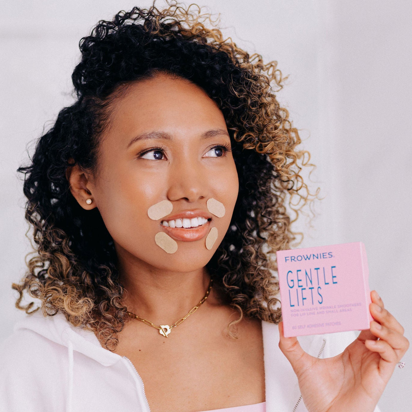 A black woman shown wearing Frownies gentle lifts while holding the Frownies package in her hand 