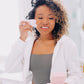 Frownies Gua Sha rose quartz stone being used by a black woman with curly hair 