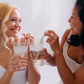 A woman with blonde hair with another woman with black hair. Both are drinking a drink using Frownies wrinkies straw tip