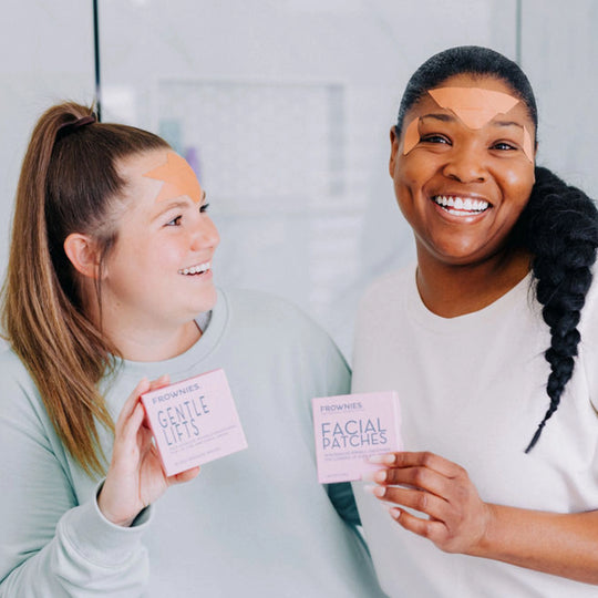 Two women models, one holding Frownies Gentle Lifts and the other holding facial patches, both wearing Frownies facial patches.