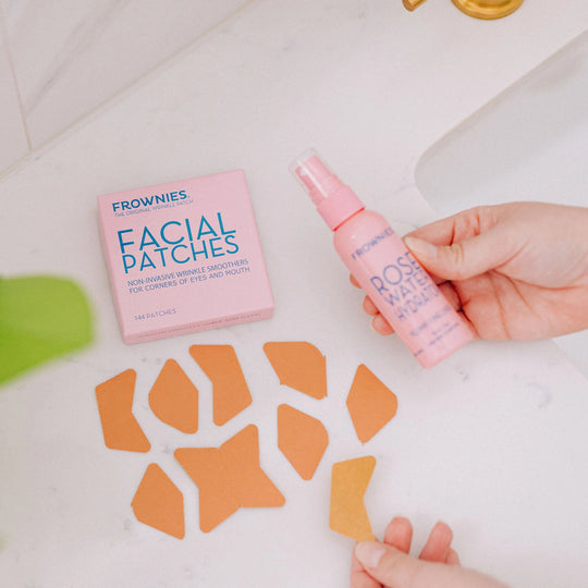 Frownies CEM (Corners of Eyes and Mouth) facial patches displayed alongside a bottle of rose water hydrator, with the patches laid out prominently.