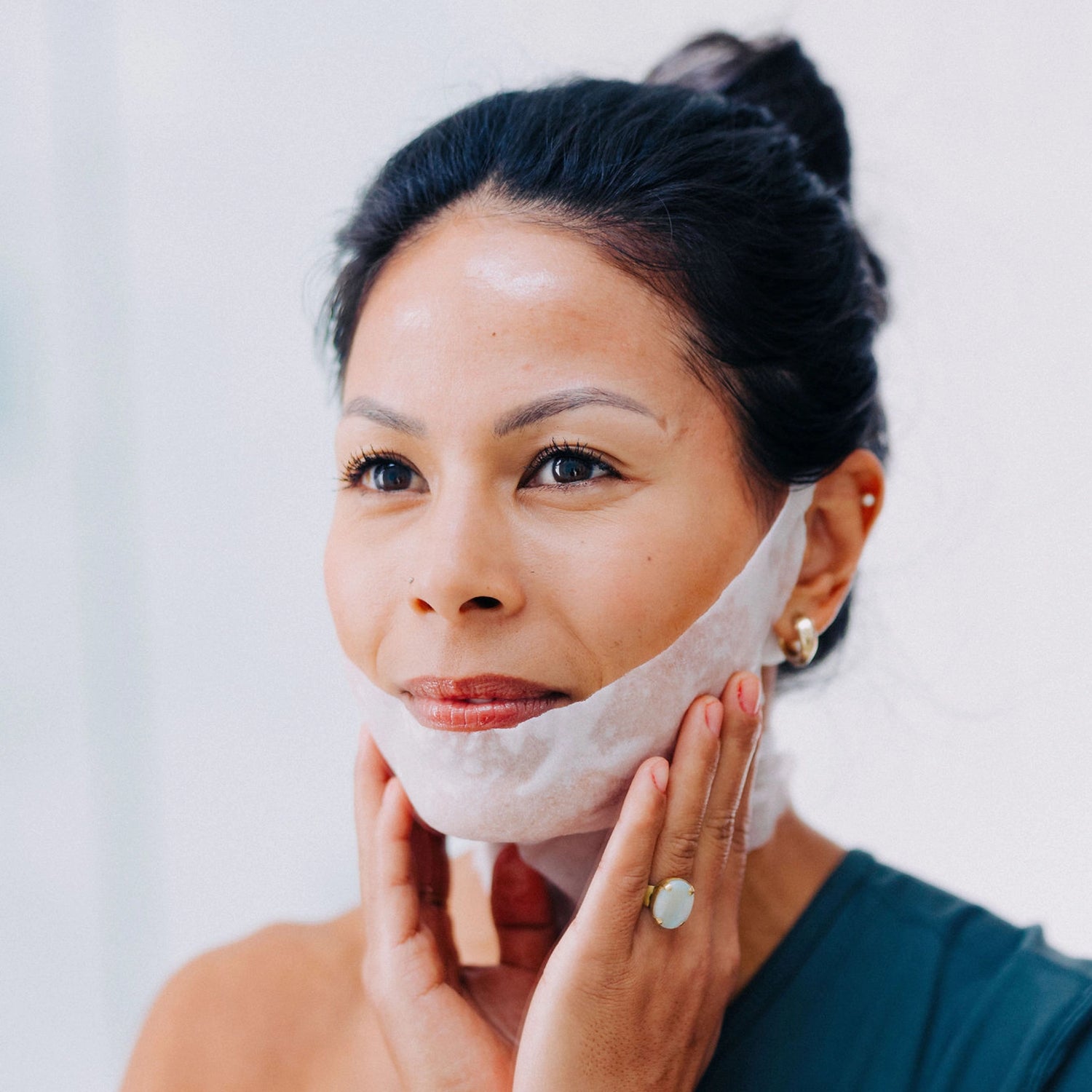 A happy model with black hair wearing a Frownies Chin-Up Polypeptide Mask.