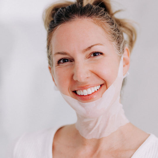 A happy model with blonde hair wearing a Frownies Chin-Up Polypeptide Mask.