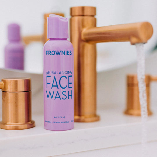 Frownies pH-balancing face wash placed on a bathroom counter next to a sink.