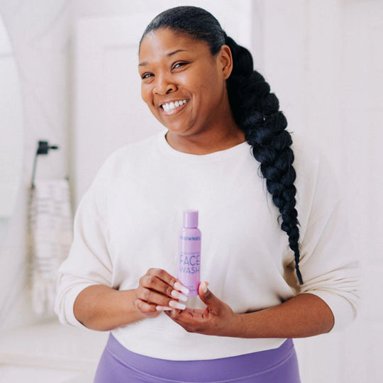 A woman smiling while holding Frownies facial wash