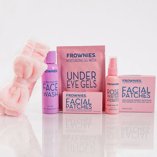 Frownies Forehead and Between Eyes (FBE) patches displayed with under-eye gels, rose water hydrator, Corners of Eyes and Mouth (CEM) patches, and a skincare headband.