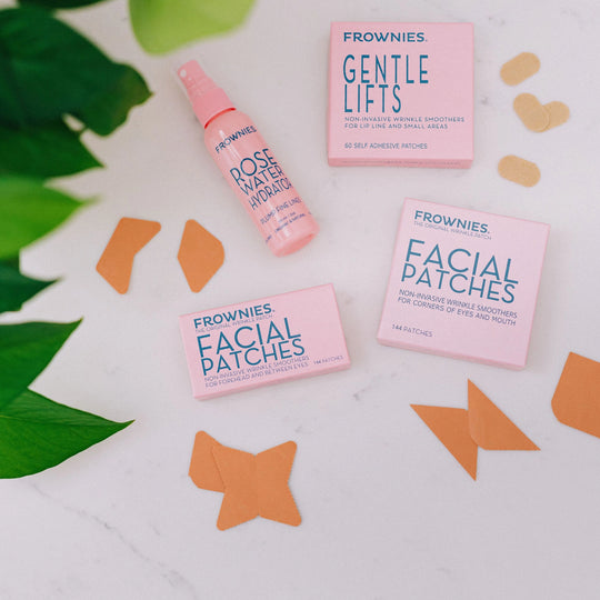 Frownies facial patches (Corners of Eyes and Mouth - CEM and Forehead and Between Eyes - FBE) laid out with rose water hydrator and Gentle Lifts.